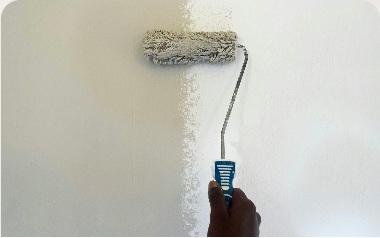 Painter applying a fresh coat of white paint to a wall